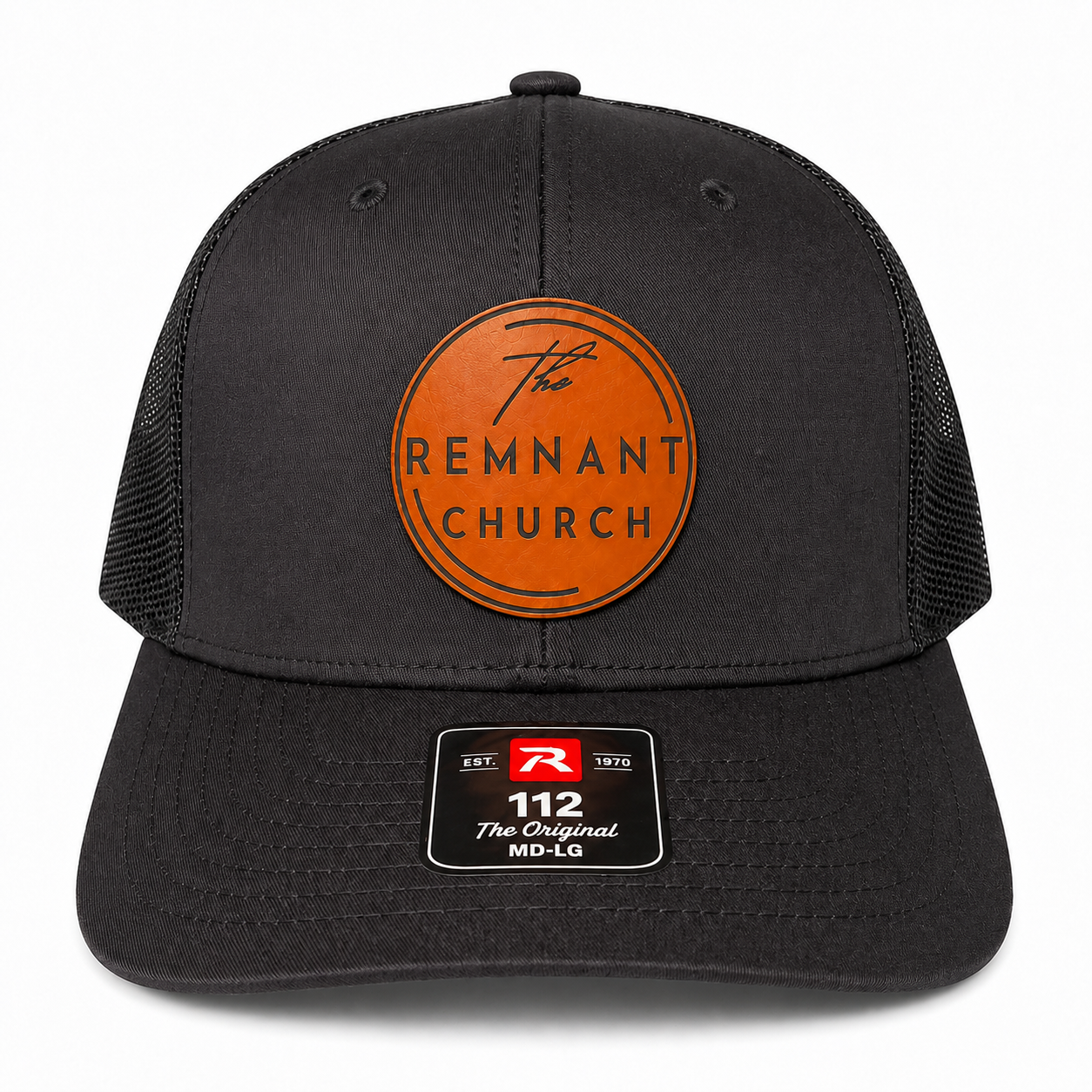 A black trucker-style cap with a curved brim, black mesh back, and a circular orange front patch reading 'The REMNANT CHURCH.' A size/brand sticker is visible on the brim.