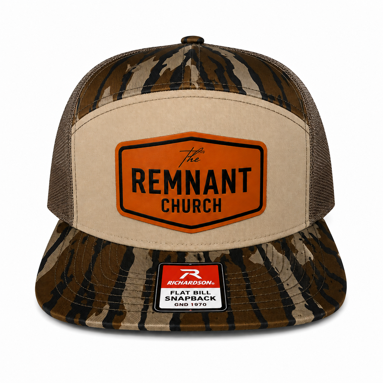 A camouflage trucker hat with a beige front panel and a prominent orange shield-shaped patch reading 'The REMNANT CHURCH.' The brim and back mesh are in a brown, beige, and black camo pattern.